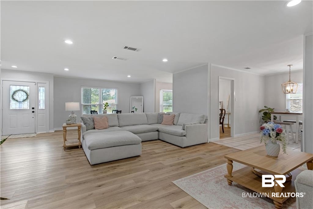 1624 Apex Drive Mobile, AL 36693 - Photo 11 of 29 Living room featuring light hardwood / wood-style floors, crown molding, and an inviting chandelier