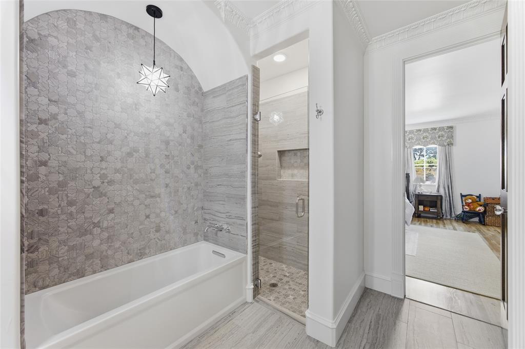 501 Upper Denton Road Weatherford, TX 76085 - Photo 22 of 40 Bathroom featuring a built-in bathtub, a walk-in shower with a glass enclosure, patterned wall tile, and stone-finish flooring