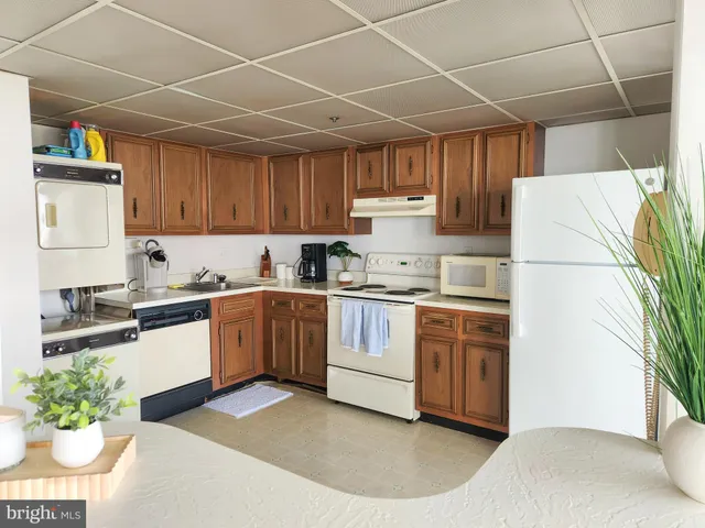 a kitchen with granite countertop a refrigerator a stove a sink dishwasher and white cabinets with wooden floor