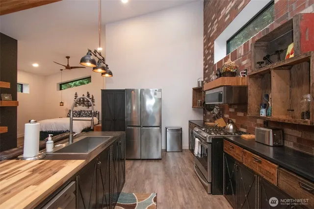 a kitchen with stainless steel appliances granite countertop a refrigerator a stove and a sink with wooden floor