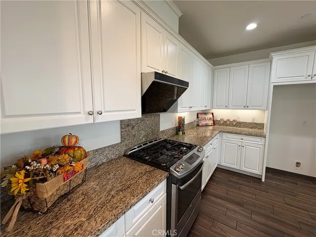 a kitchen with granite countertop a stove and a wooden floor
