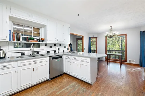 a kitchen with cabinets stainless steel appliances and wooden floor