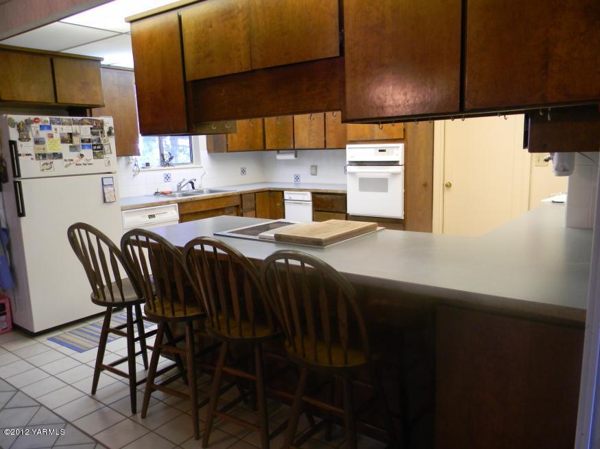 991 Olmstead Road Grandview, WA 98930 - Photo 3 of 17 a kitchen with stainless steel appliances a table chairs and a refrigerator