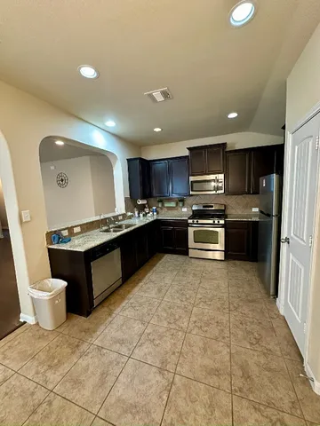 a kitchen with stainless steel appliances granite countertop a refrigerator and a stove