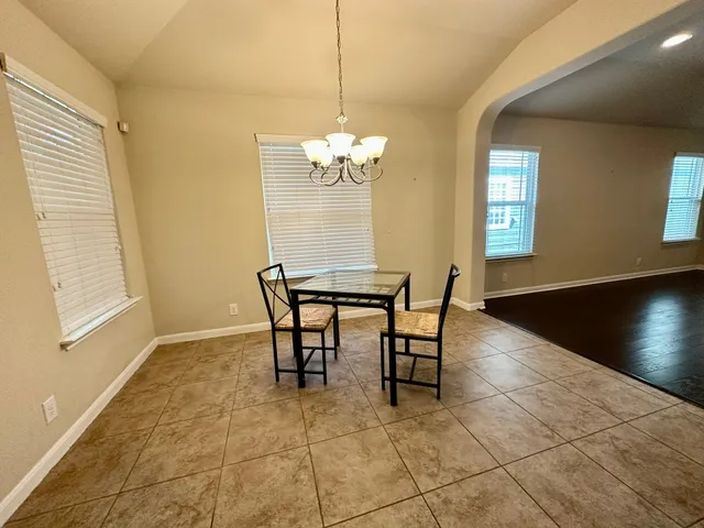 a dining room with chandelier and wooden floor