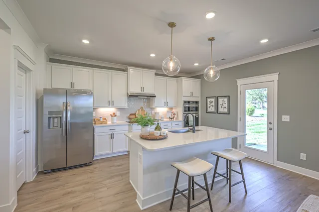 a kitchen with stainless steel appliances a dining table chairs stove refrigerator and cabinets