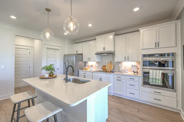 a kitchen with stainless steel appliances kitchen island granite countertop a sink a stove a dining table and chairs