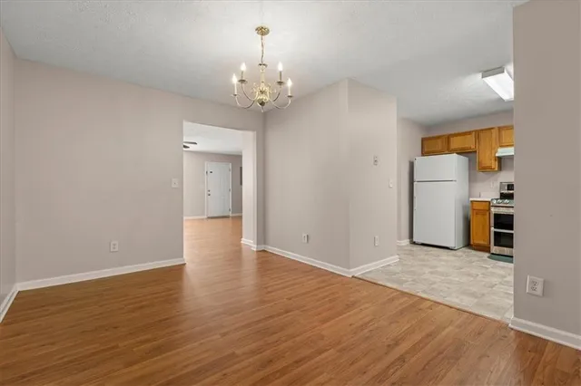 a view of a hallway with wooden floor and a kitchen