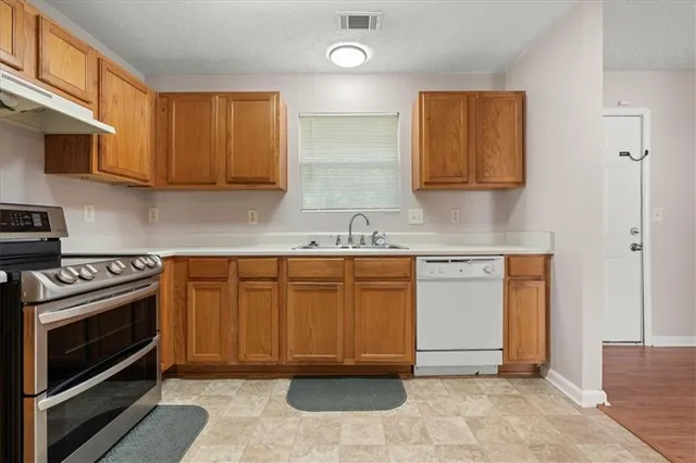 a kitchen with granite countertop a stove top oven cabinets and stainless steel appliances