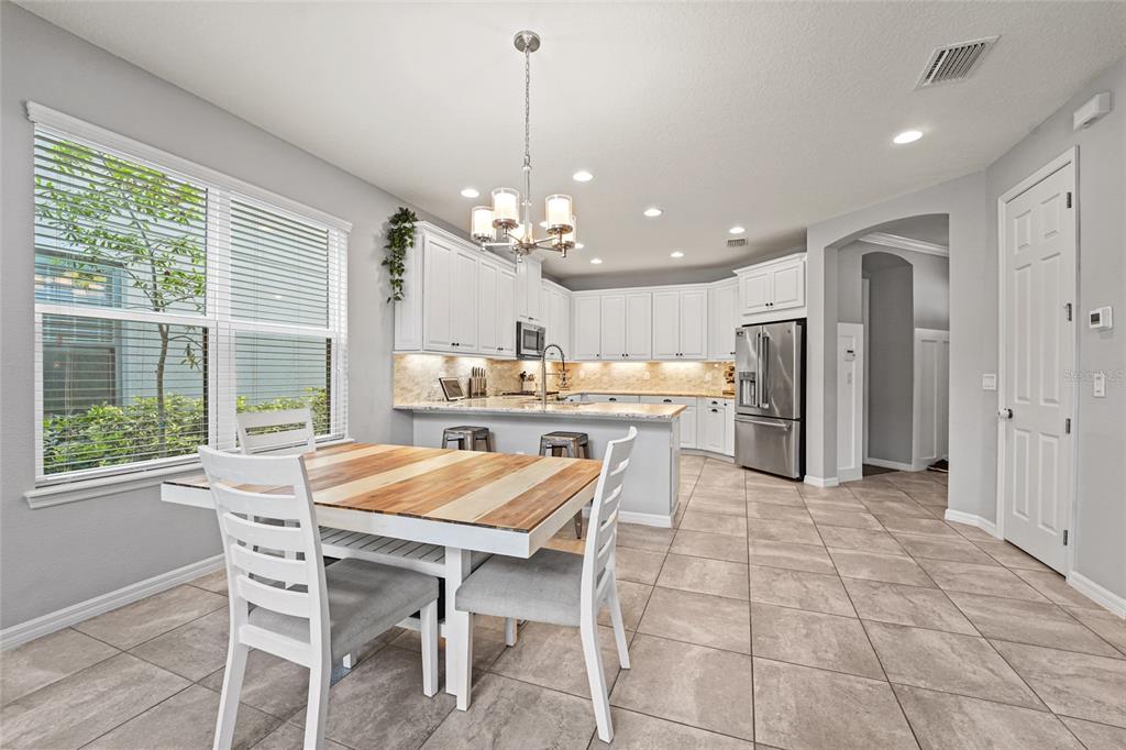 8903 Arabella Lane Seminole, FL 33777 - Photo 21 of 47 a dining room with stainless steel appliances kitchen island granite countertop a table chairs and a refrigerator