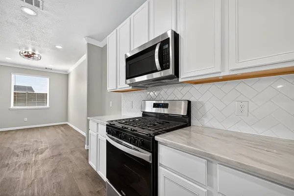 a kitchen with a sink stove microwave and cabinets