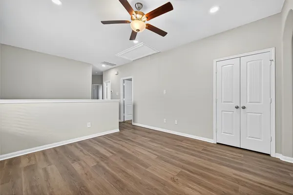 an empty room with wooden floor and a ceiling fan