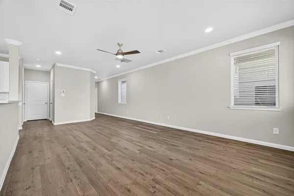 an empty room with wooden floor ceiling fan and windows