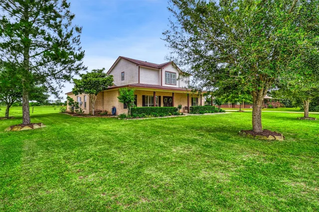 a front view of a house with garden and trees