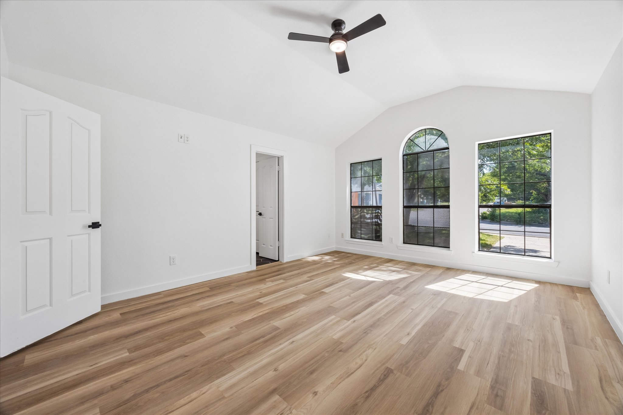 1706 Davis Street Taylor, TX 76574 - Photo 8 of 18 Natural light floods this primary suite, featuring vaulted ceilings and durable plank flooring.