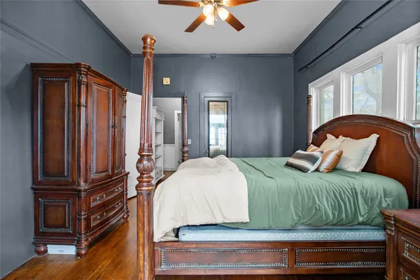 a bedroom with a bed and dresser with wooden floor