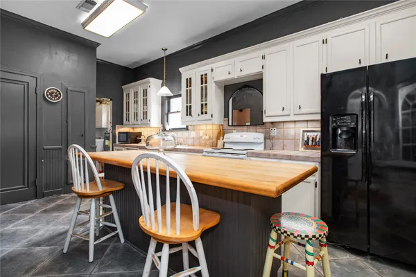a kitchen with stainless steel appliances granite countertop a dining table chairs refrigerator and sink