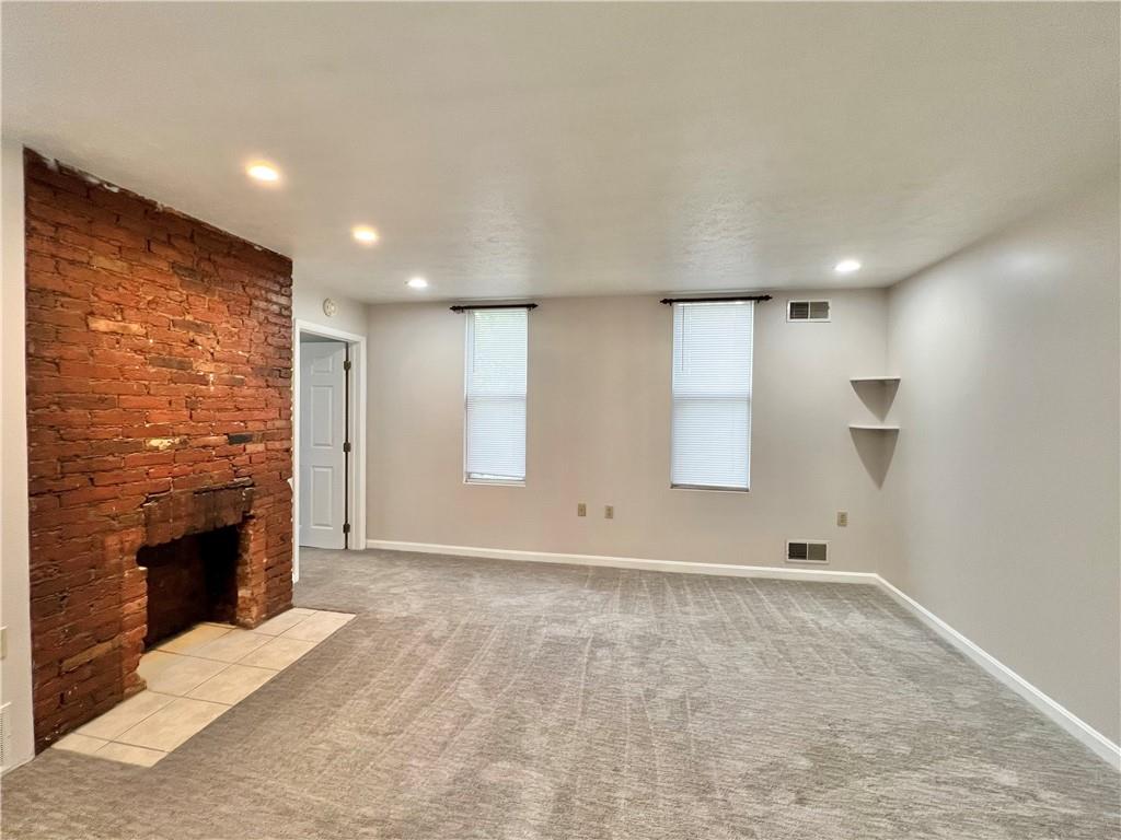 a view of an empty room with a fireplace and a window