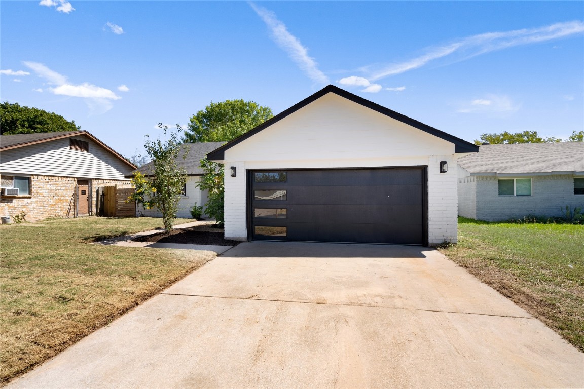 Ranch-style home with a front yard, a garage, and brick siding