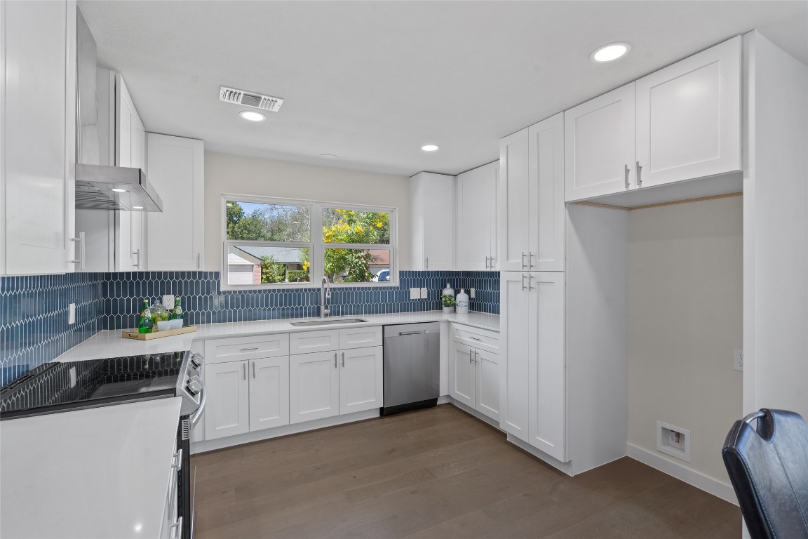 6901 Windrift Way Austin, TX 78745 - Photo 11 of 30 Kitchen with stainless steel appliances, white cabinets, wall chimney range hood, dark wood finished floors, and recessed lighting