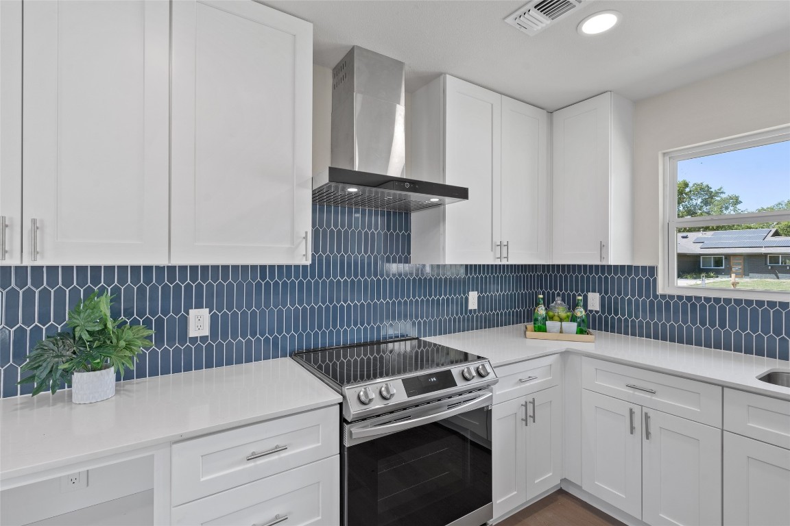 6901 Windrift Way Austin, TX 78745 - Photo 12 of 30 Kitchen with white cabinetry, stainless steel range with electric stovetop, wall chimney exhaust hood, light stone counters, and recessed lighting