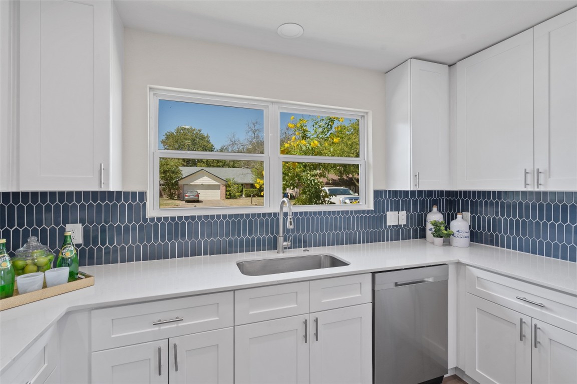 6901 Windrift Way Austin, TX 78745 - Photo 15 of 30 Kitchen with white cabinetry, dishwasher, light stone counters, and decorative backsplash