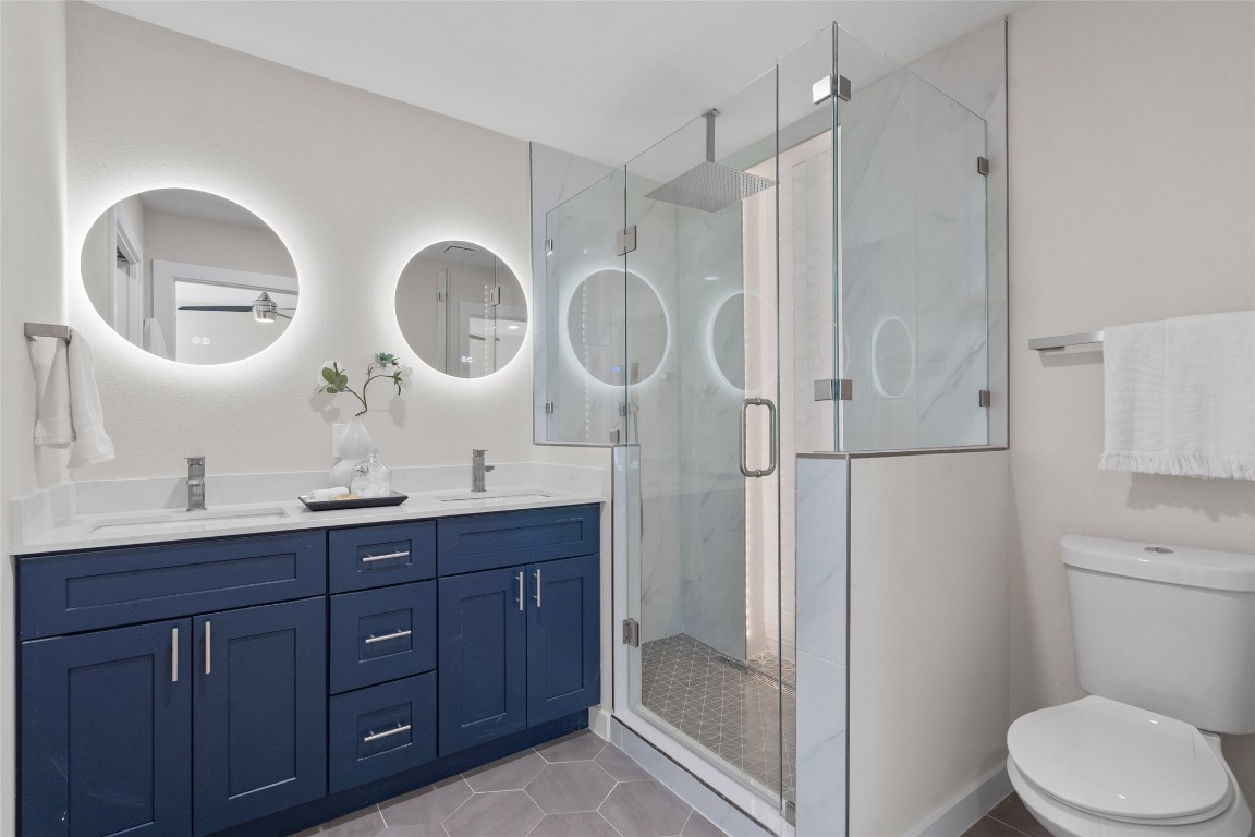 6901 Windrift Way Austin, TX 78745 - Photo 20 of 30 Bathroom featuring a marble finish shower, double vanity, and light tile patterned floors