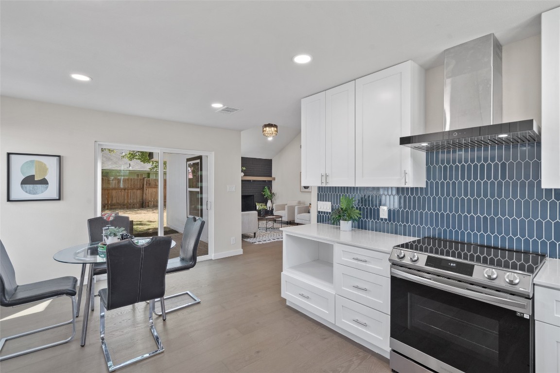 6901 Windrift Way Austin, TX 78745 - Photo 5 of 30 Kitchen featuring electric stove, wall chimney range hood, white cabinets, decorative backsplash, and recessed lighting