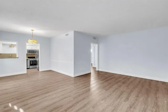 an empty room with wooden floor closet and windows