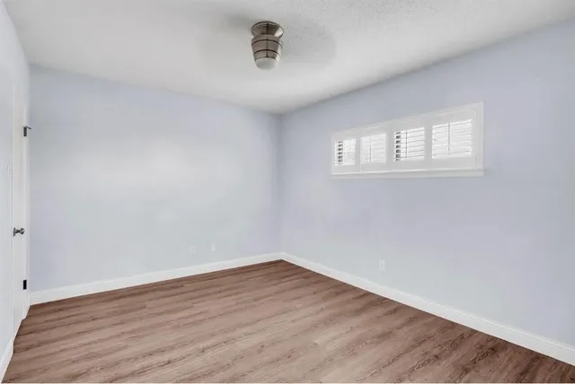 a view of a room that has wooden floor and a window