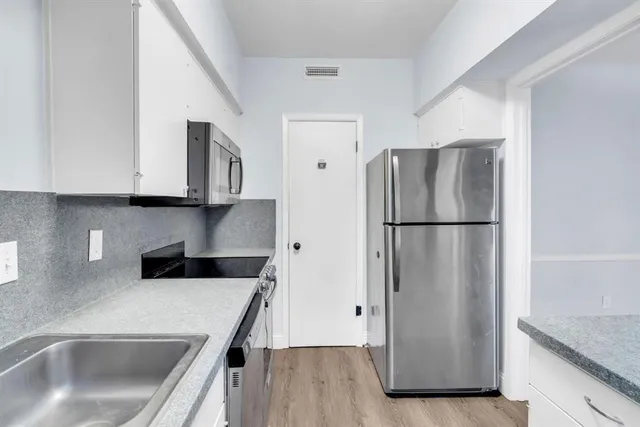 a kitchen with stainless steel appliances granite countertop a refrigerator a sink a stove and cabinets