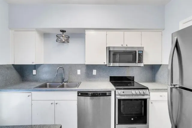 a kitchen with appliances a sink and cabinets