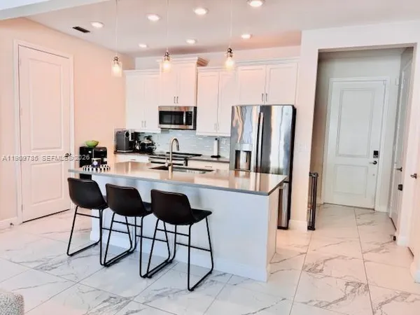 a kitchen with stainless steel appliances kitchen island granite countertop a refrigerator and a stove top oven
