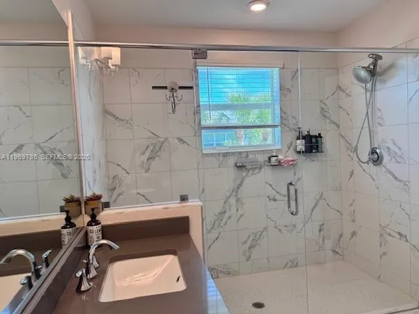 a bathroom with a tub sink a window and a shower