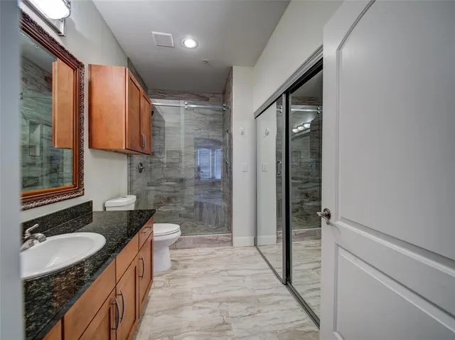 a bathroom with a granite countertop sink toilet and shower