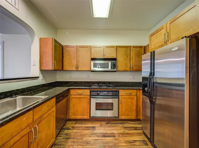 a kitchen with stainless steel appliances granite countertop a refrigerator sink and stove