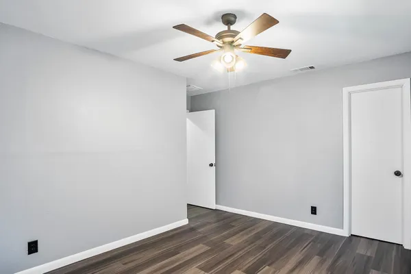an empty room with wooden floor and ceiling fan
