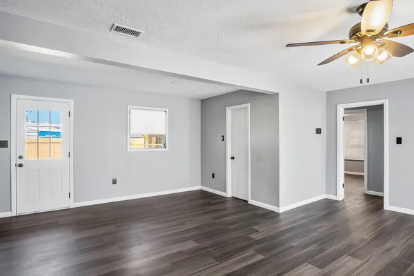 a view of an empty room with window and wooden floor