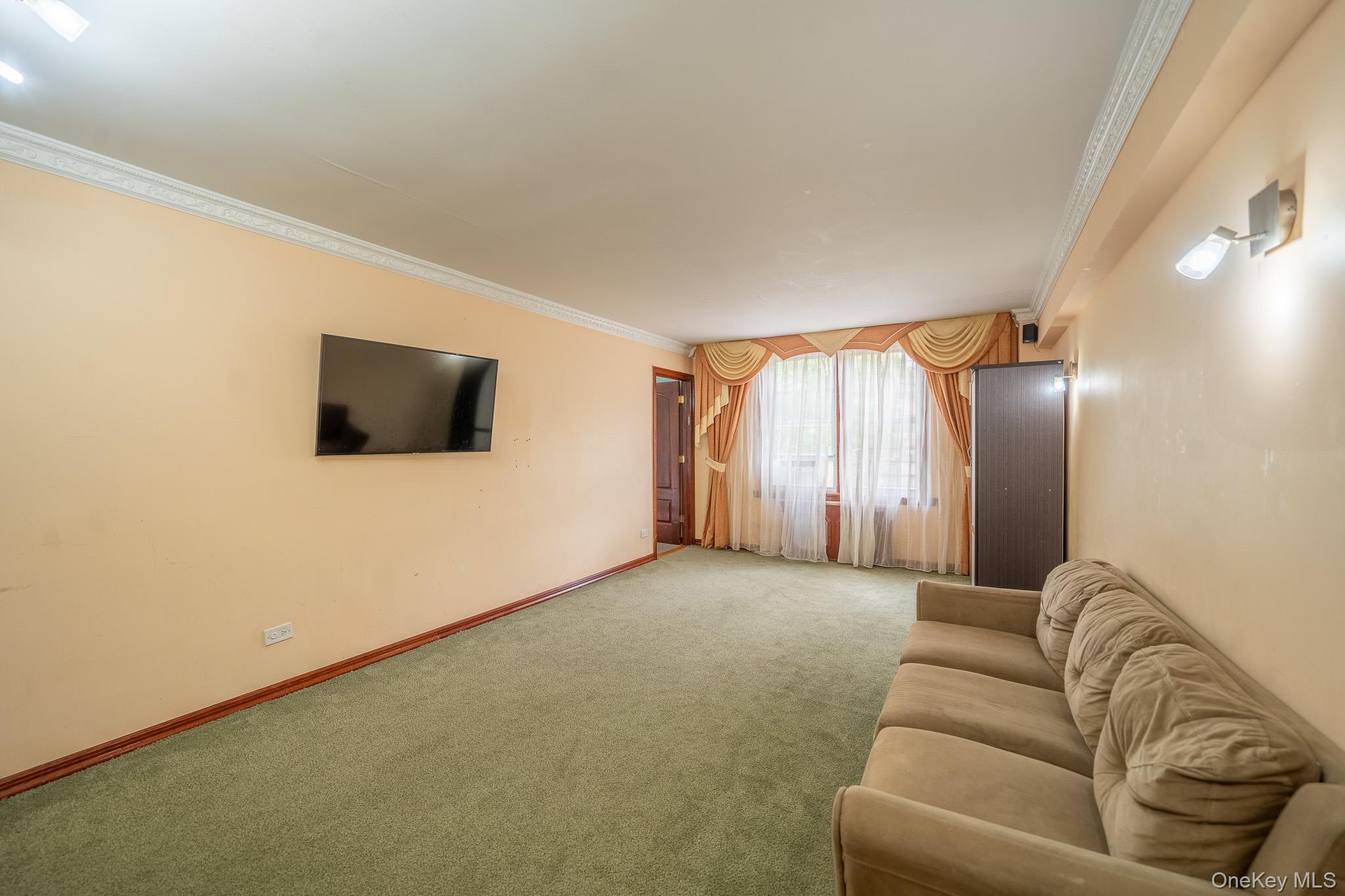 62-59 108th Street, Unit 4N Queens, NY 11375 - Photo 2 of 10 a living room with a flat screen tv a lamp and a window