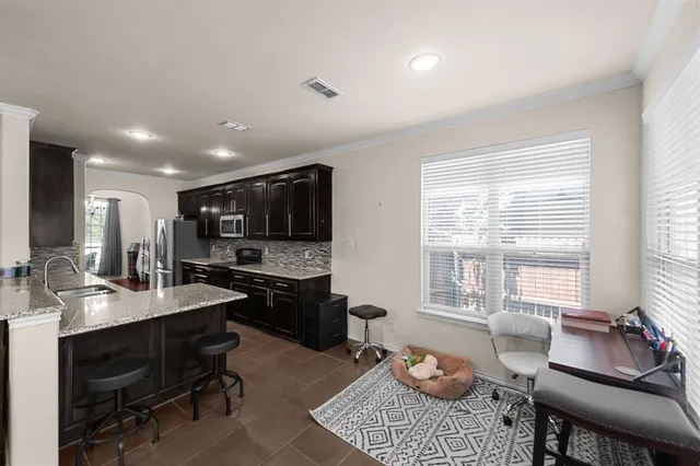 a kitchen with stainless steel appliances kitchen island granite countertop a table chairs sink and cabinets
