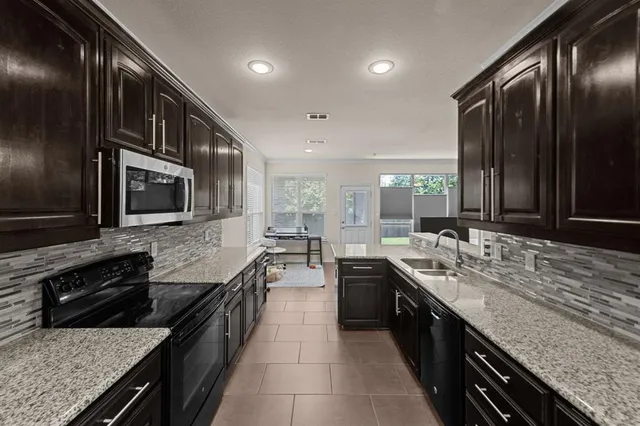 a large kitchen with granite countertop a stove and a sink