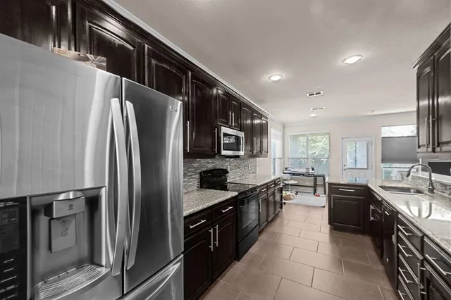 a kitchen with stainless steel appliances granite countertop a refrigerator a sink a stove and oven