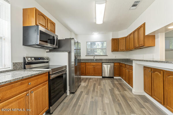 1330 Eddy Road Jacksonville, FL 32211 - Photo 16 of 39 a kitchen with stainless steel appliances granite countertop wooden cabinets a sink dishwasher a stove and a refrigerator with wooden floor