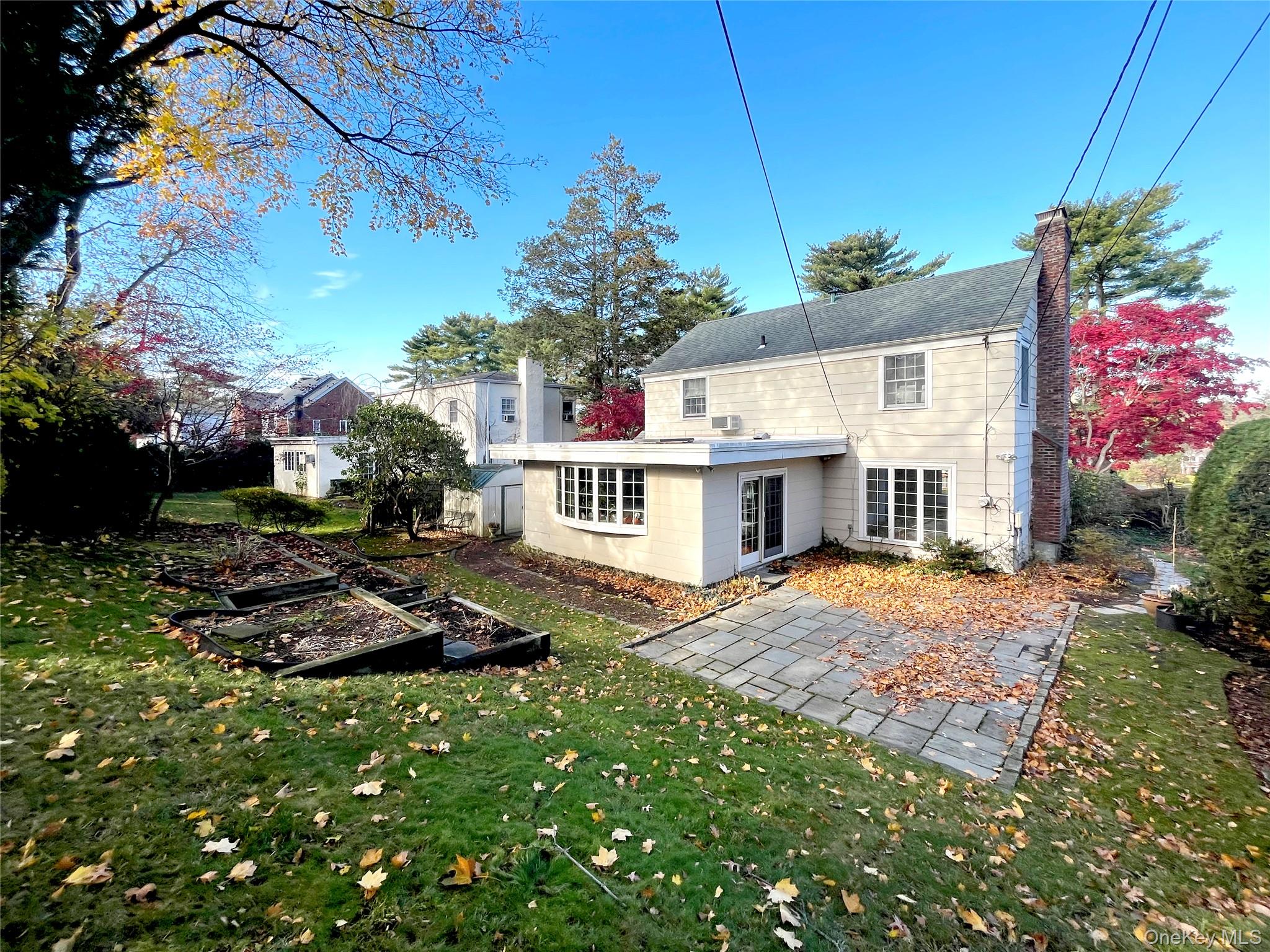 146 Quaker Ridge Road Manhasset, NY 11030 - Photo 3 of 3 Back of house featuring a chimney, a yard, a garden, and a patio area