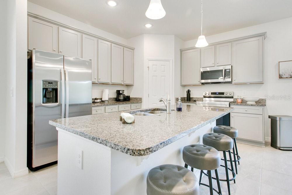 3964 Mayhill Loop Eustis, FL 32736 - Photo 11 of 34 a kitchen with stainless steel appliances granite countertop a sink refrigerator and cabinets