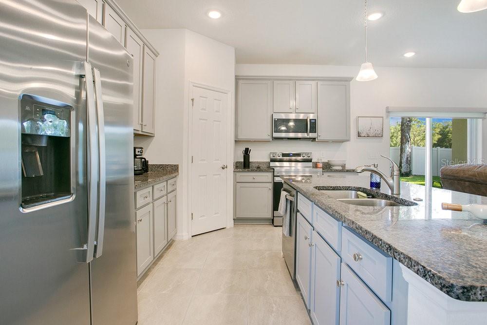3964 Mayhill Loop Eustis, FL 32736 - Photo 10 of 34 a kitchen with stainless steel appliances granite countertop a refrigerator a sink dishwasher a stove and white cabinets with wooden floor