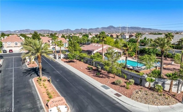 10247 Rising Tree Street Las Vegas, NV 89183 - Photo 5 of 7 An aerial perspective reveals a serene community pool with abundant landscaping and mountain views.