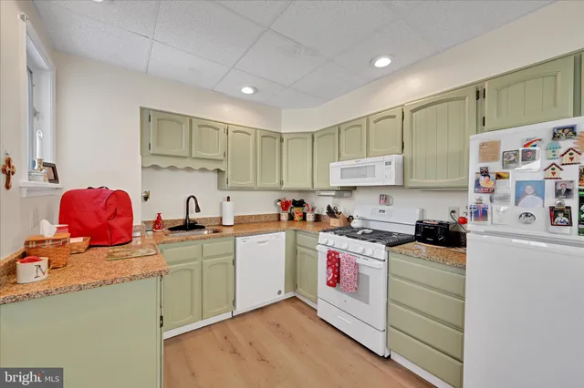 a kitchen with cabinets a sink and white appliances