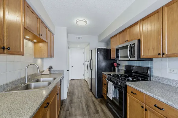 a kitchen with stainless steel appliances a sink a stove a refrigerator cabinets and a sink