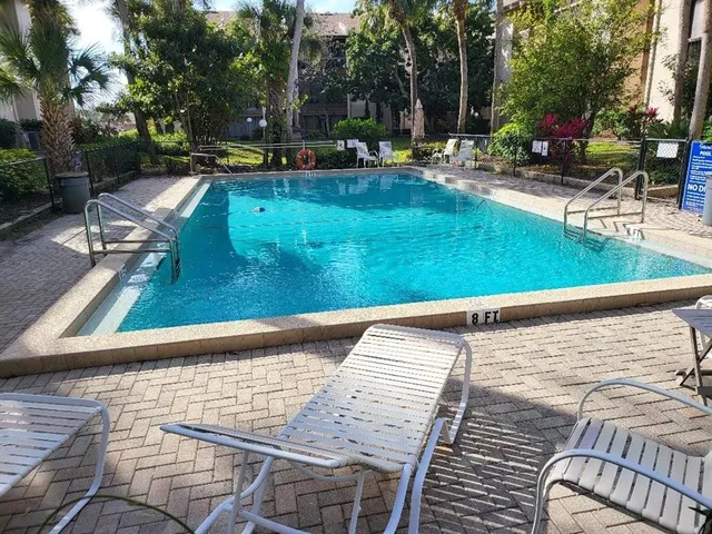 a view of swimming pool with lawn chairs and plants